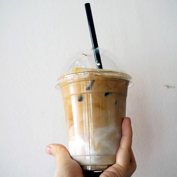 A hand holding up an iced latte